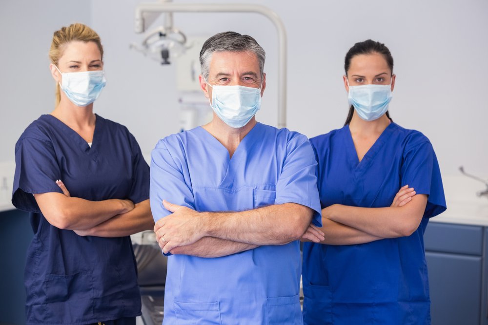 Co-workers wearing surgical mask with arms crossed in dental clinic