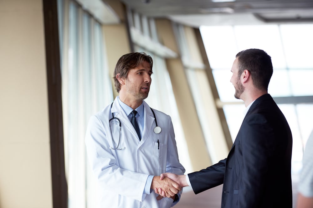 doctor handshake with a patient at doctors bright modern office in hospital-1